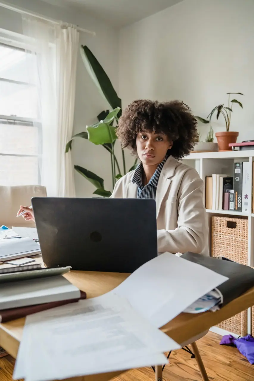 Person arbetar med laptop och dokument vid skrivbord