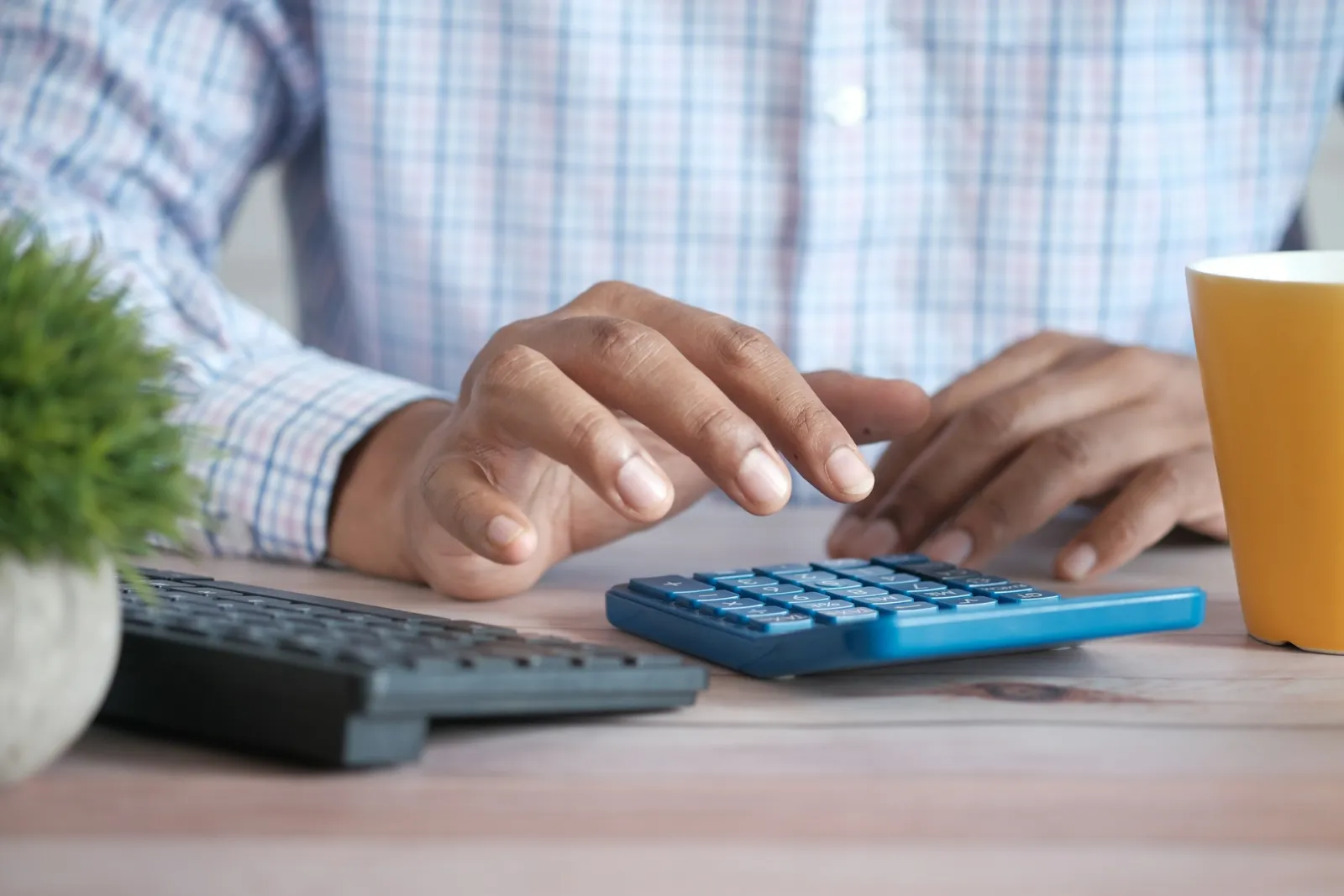 Närbild på en hand som slår in siffror på en miniräknare vid ett skrivbord